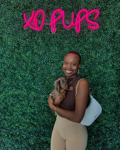 Woman smiling while holding a puppy at XO Pups